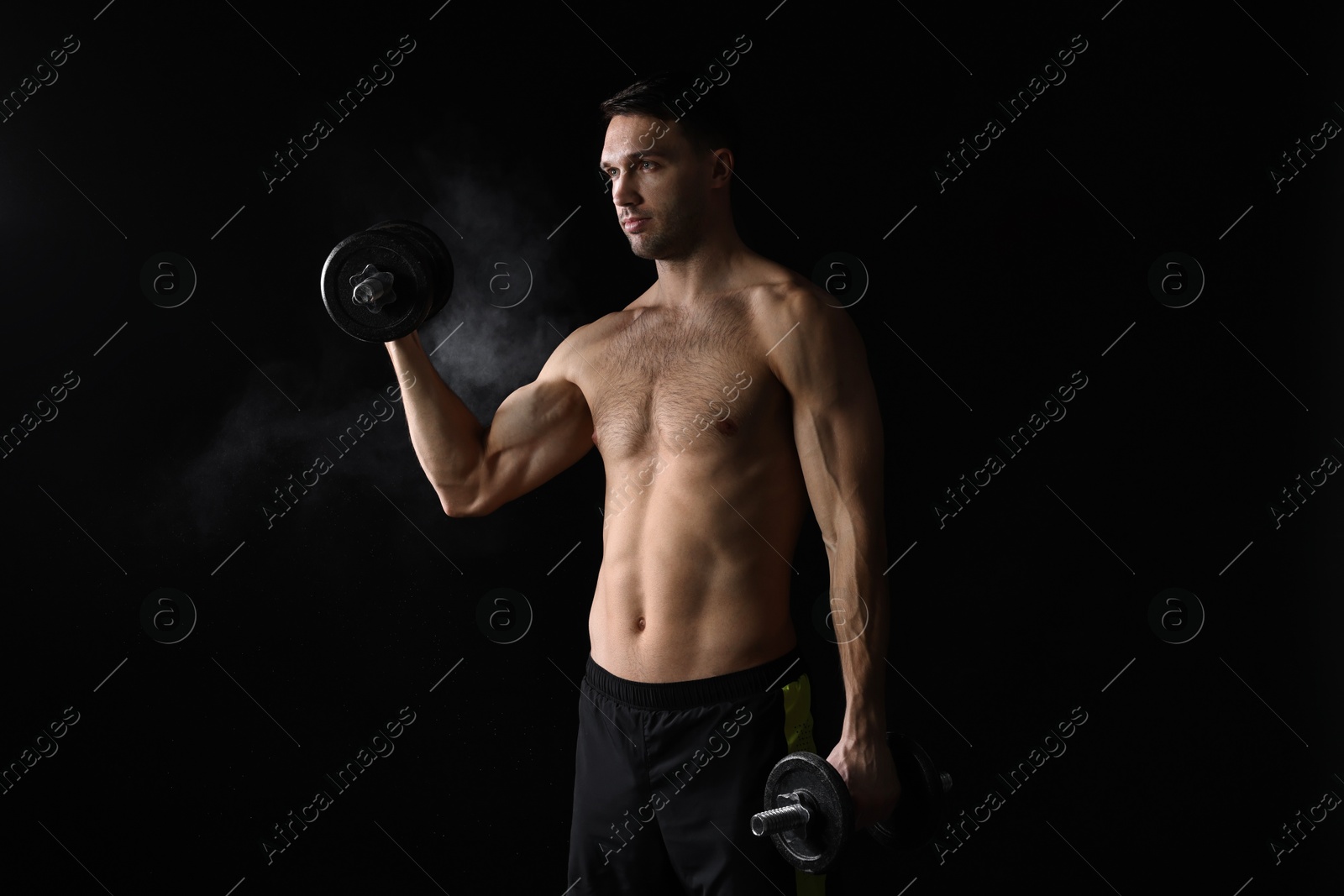 Photo of Man training with barbell on black background