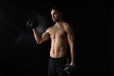 Man training with barbell on black background