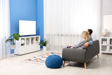 Photo of Lovely couple watching tv on couch at home