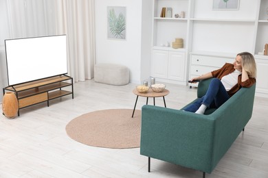 Photo of Woman with snacks and drinks watching tv on couch at home