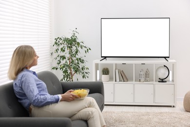 Photo of Woman with chips watching tv on couch at home