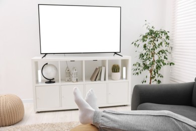 Woman watching tv on couch at home, closeup