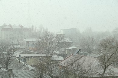 Buildings and trees under falling snow on city street