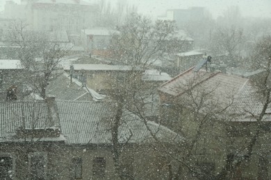 Buildings and trees under falling snow on city street