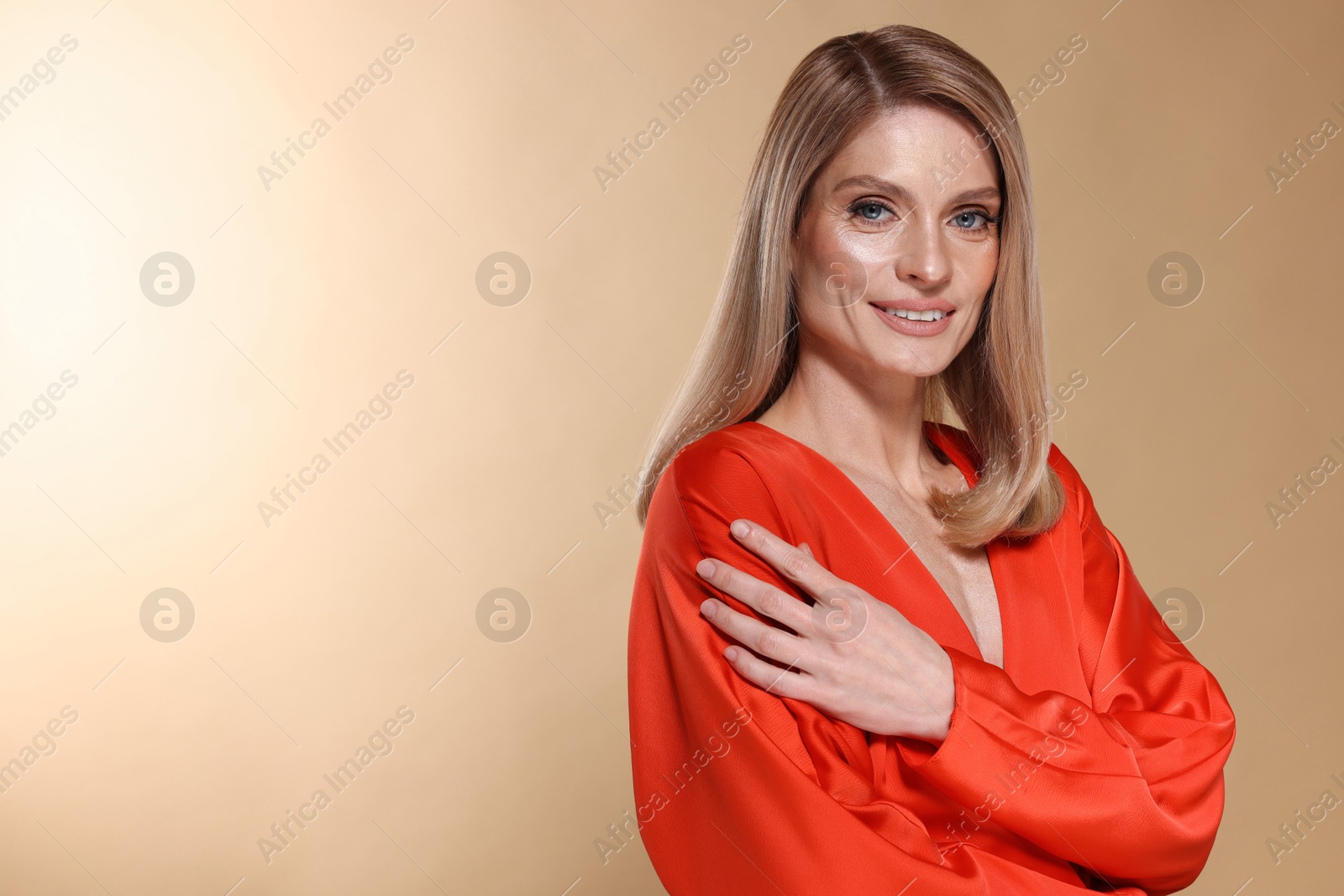 Photo of Portrait of beautiful happy woman with straight blonde hair on beige background, space for text