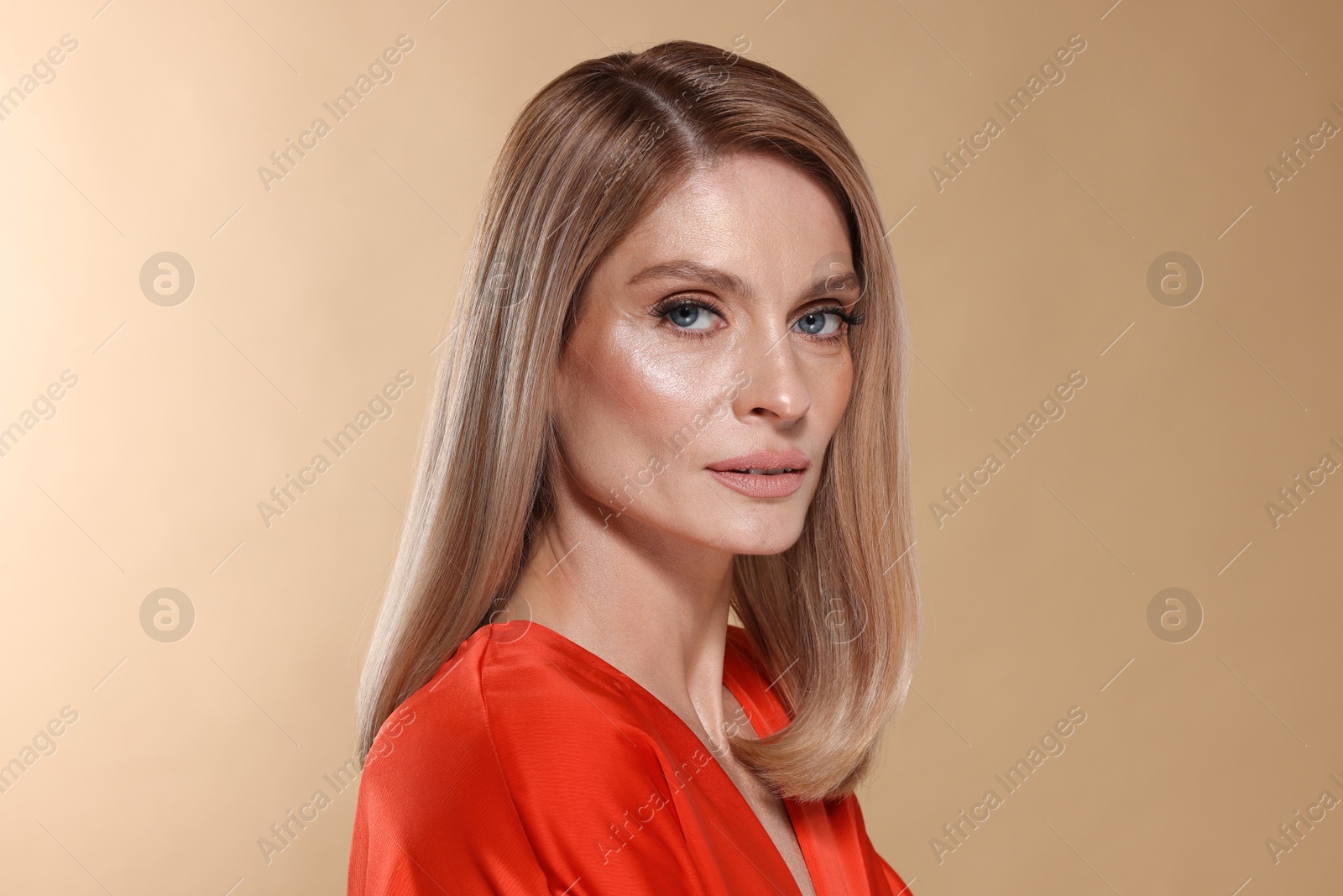 Photo of Beautiful woman with straight blonde hair on beige background