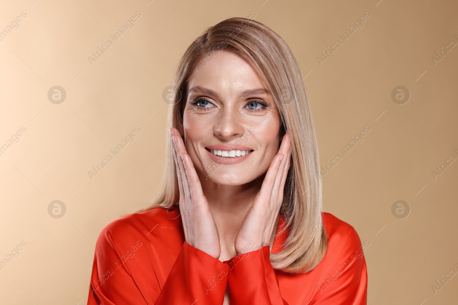 Photo of Portrait of beautiful happy woman with straight blonde hair on beige background