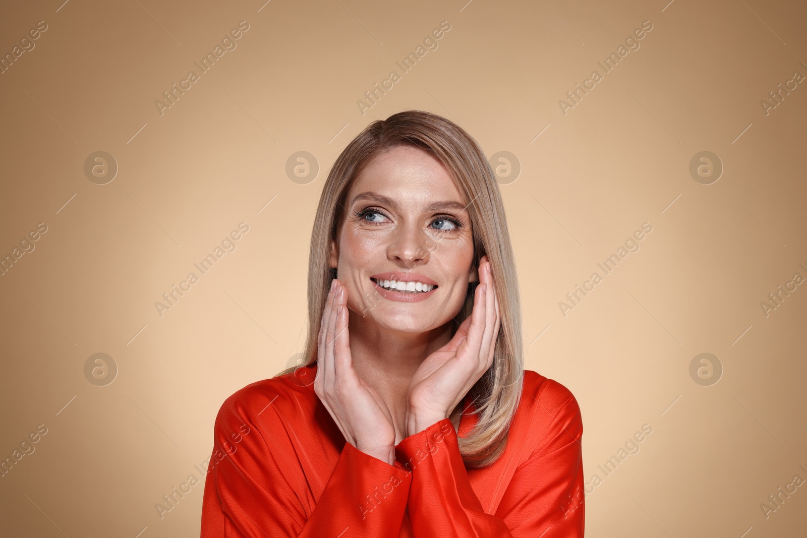 Photo of Portrait of beautiful happy woman with straight blonde hair on beige background