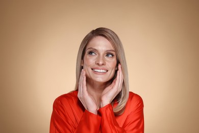 Portrait of beautiful happy woman with straight blonde hair on beige background