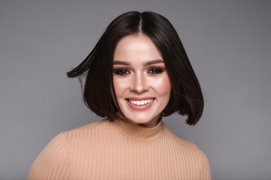 Photo of Portrait of beautiful young happy woman with gorgeous straight hair on grey background