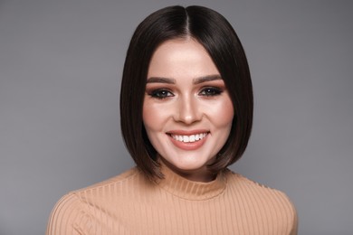 Photo of Portrait of beautiful young happy woman with gorgeous straight hair on grey background