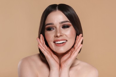 Portrait of beautiful young happy woman with gorgeous straight hair on beige background