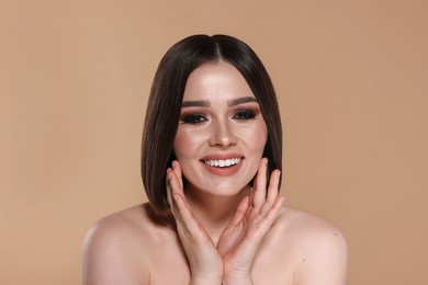 Portrait of beautiful young happy woman with gorgeous straight hair on beige background