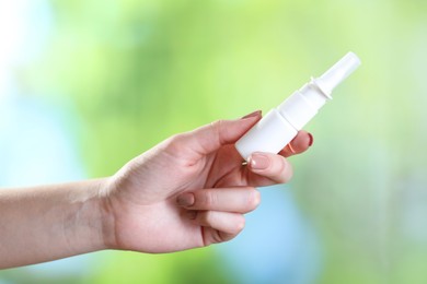 Photo of Allergy treatment. Woman with nasal spray on blurred background, closeup