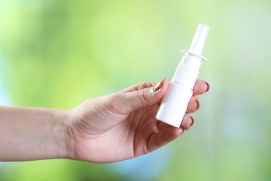 Photo of Allergy treatment. Woman with nasal spray on blurred background, closeup