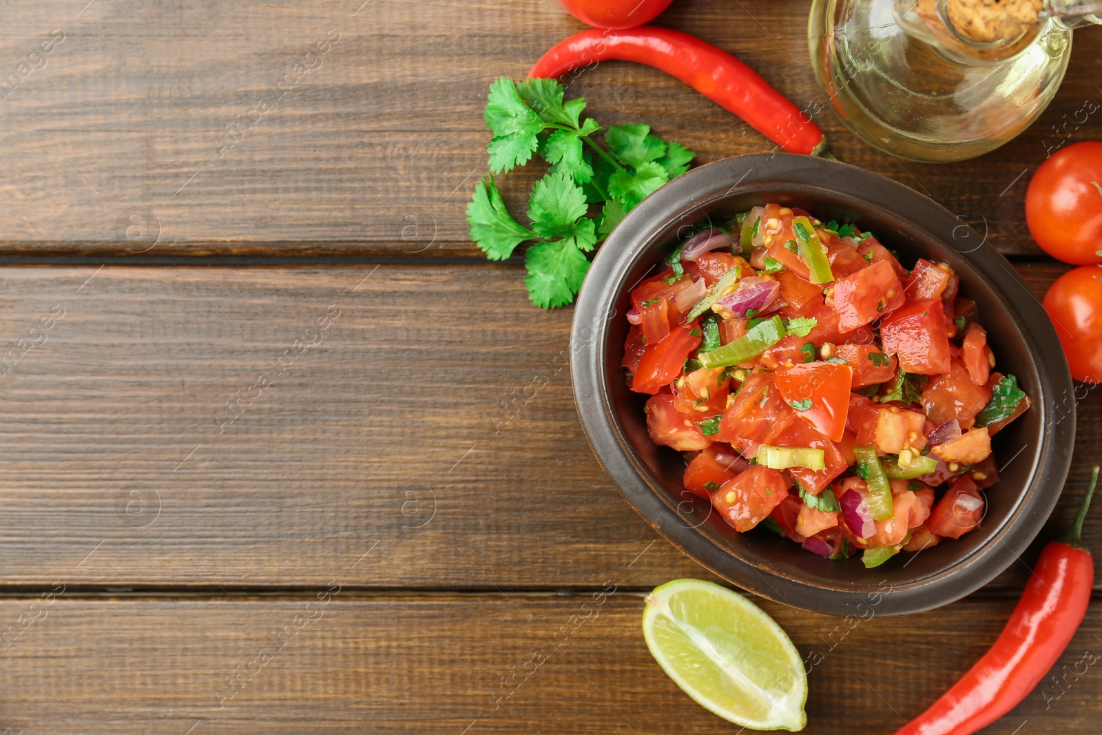 Photo of Delicious spicy salsa with ingredients on wooden table, flat lay. Space for text