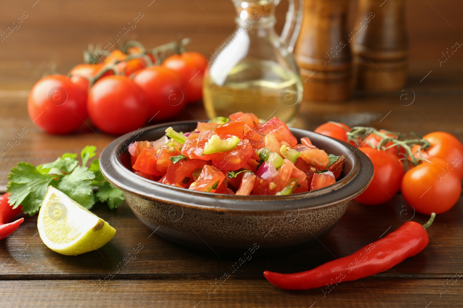 Photo of Delicious spicy salsa with ingredients on wooden table