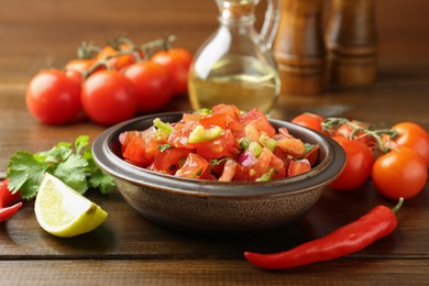 Photo of Delicious spicy salsa with ingredients on wooden table