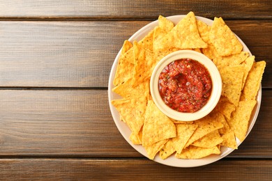 Photo of Delicious salsa with nachos on wooden table, top view. Space for text