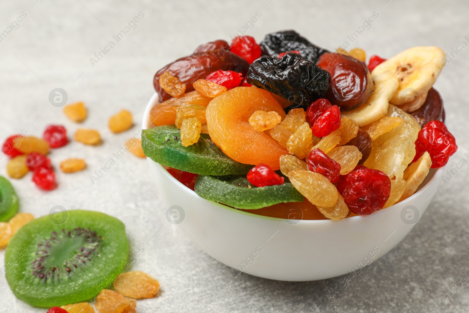 Photo of Mix of different dried fruits in bowl on grey table, closeup