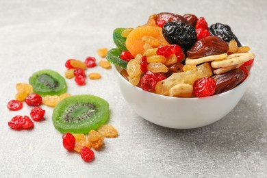 Photo of Mix of different dried fruits in bowl on grey table, closeup