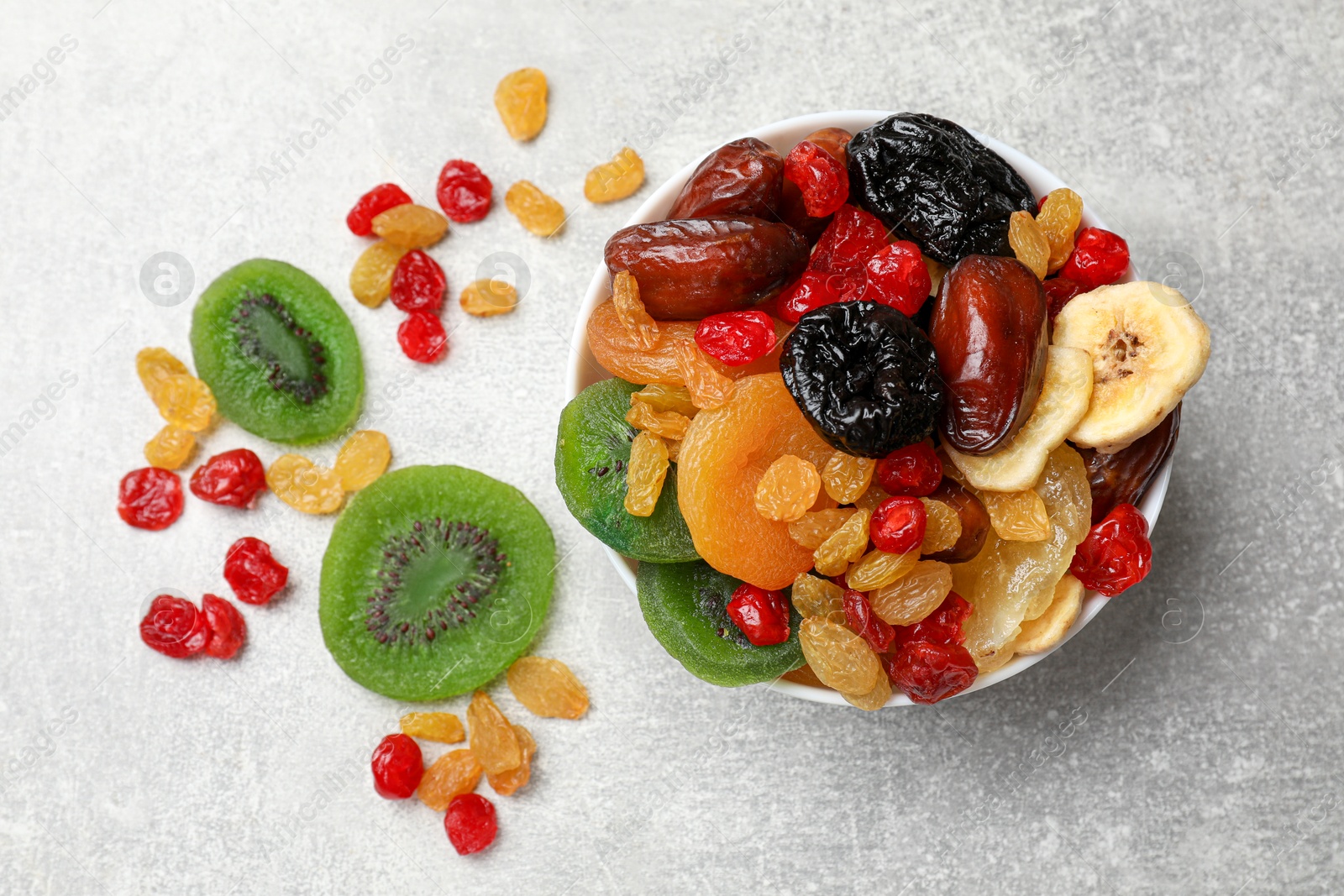 Photo of Mix of different dried fruits in bowl on grey table, top view