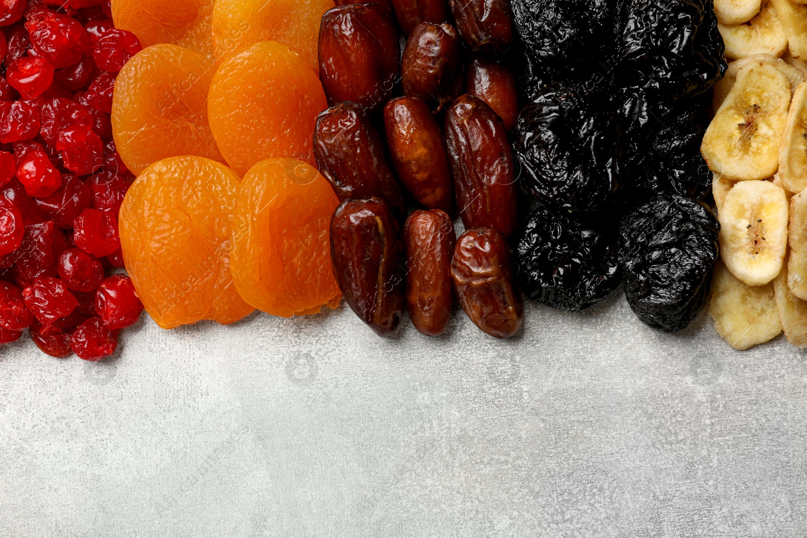 Photo of Different dried fruits on grey table, top view. Space for text