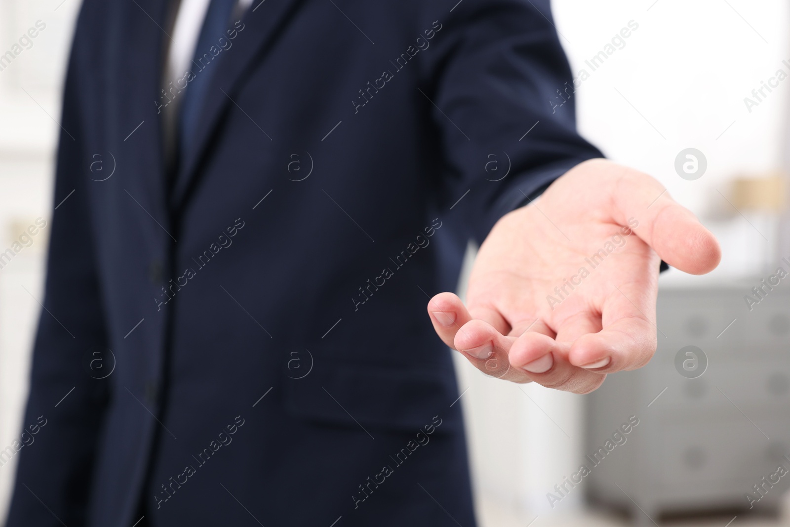 Photo of Offering help. Man reaching his hand indoors, closeup