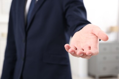 Photo of Offering help. Man reaching his hand indoors, closeup