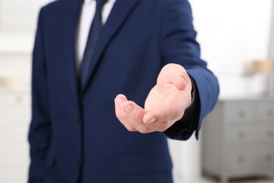 Photo of Offering help. Man reaching his hand indoors, closeup