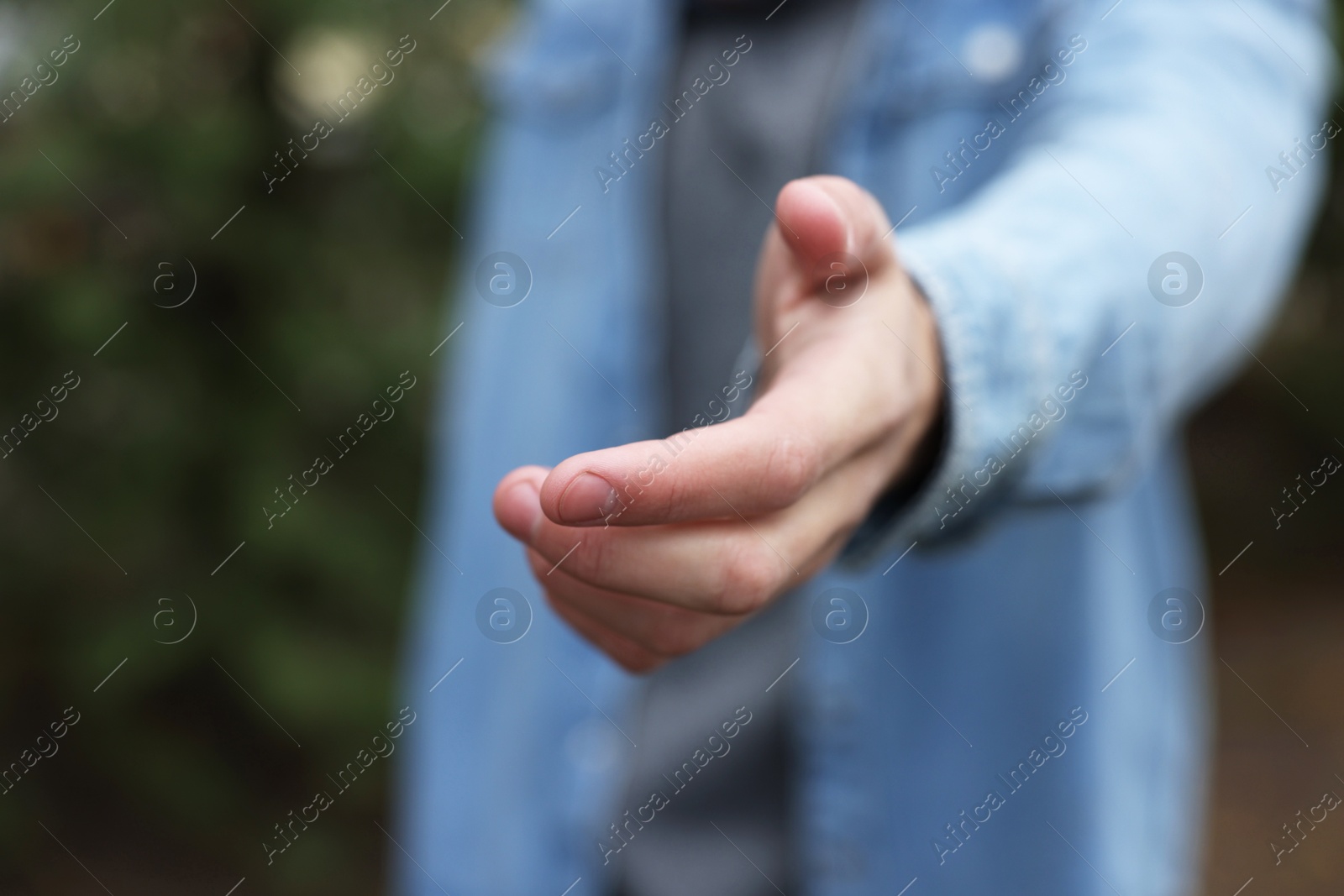 Photo of Offering help. Man reaching his hand outdoors, closeup