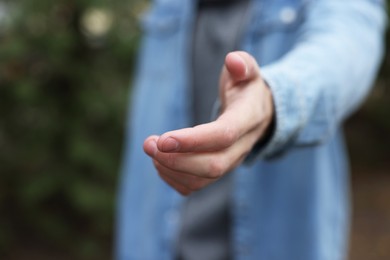 Photo of Offering help. Man reaching his hand outdoors, closeup