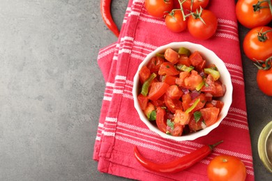 Photo of Delicious salsa (Pico de gallo) in bowl and ingredients on grey textured table, flat lay. Space for text