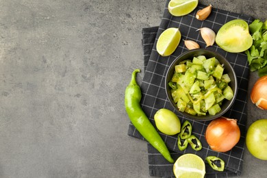 Photo of Delicious salsa (Pico de gallo) in bowl and products on grey textured table, flat lay. Space for text