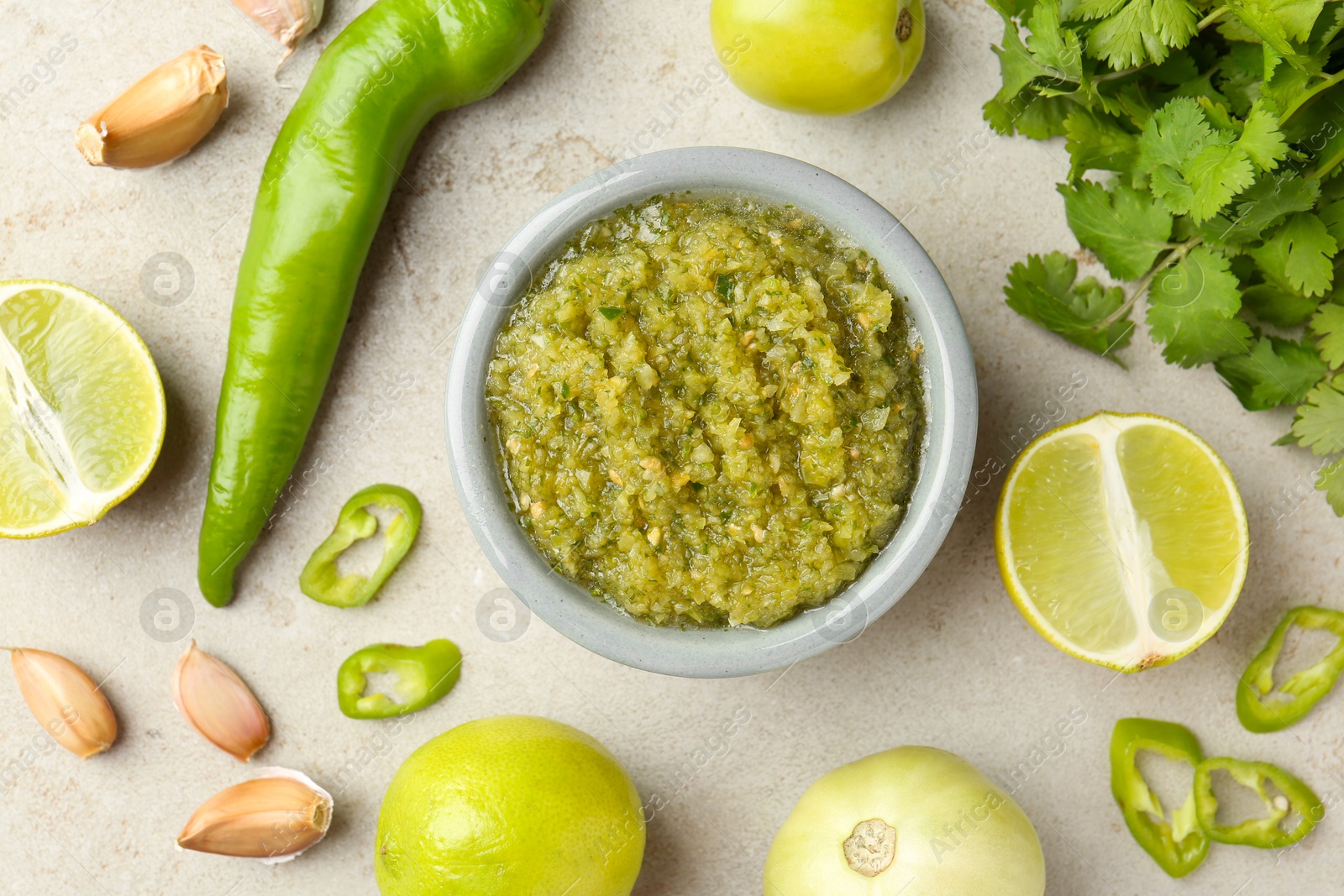 Photo of Delicious salsa sauce in bowl and ingredients on light textured table, flat lay