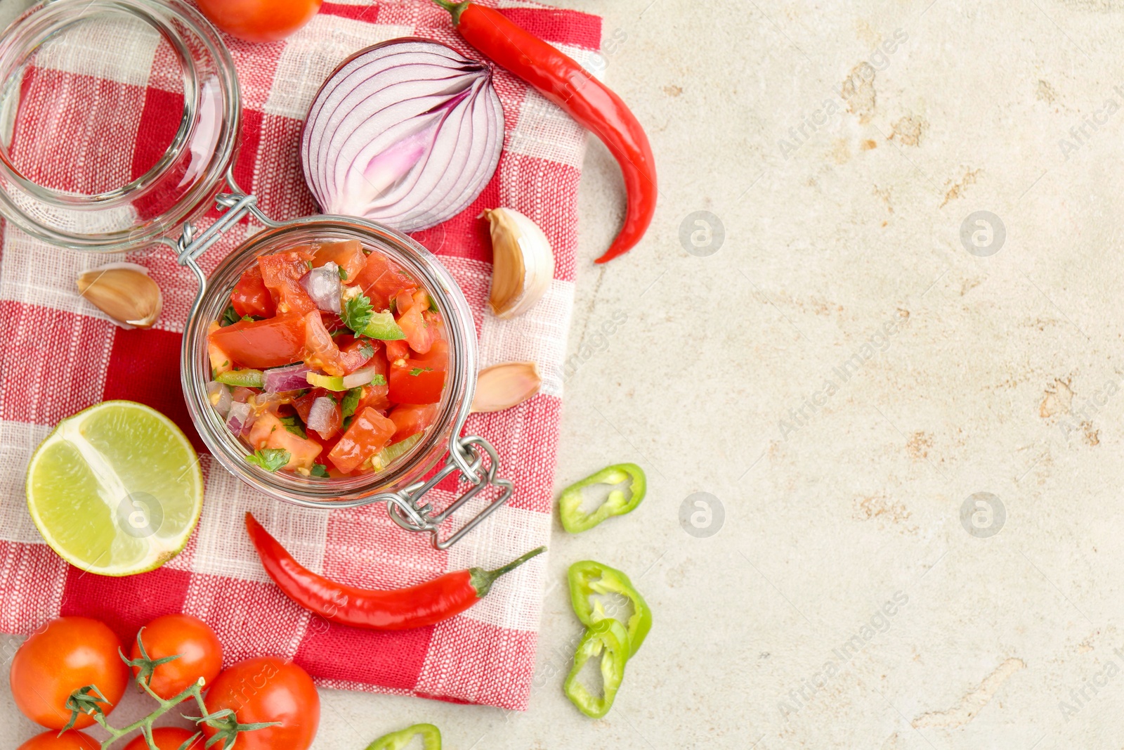 Photo of Delicious salsa (Pico de gallo) in jar and ingredients on light textured table, flat lay. Space for text