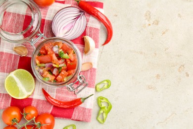 Photo of Delicious salsa (Pico de gallo) in jar and ingredients on light textured table, flat lay. Space for text