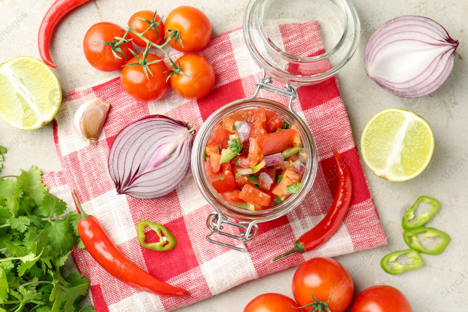 Photo of Delicious salsa (Pico de gallo) in jar and ingredients on light textured table, flat lay