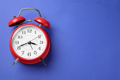 Photo of One red alarm clock on blue background, top view. Space for text