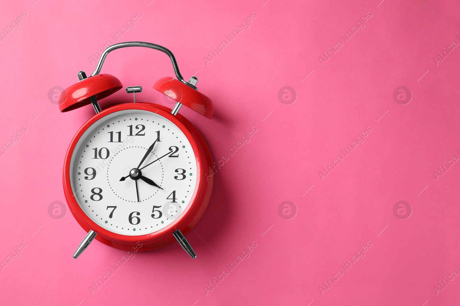 Red alarm clock on pink background, top view. Space for text Photo of Red alarm clock on pink background, top view. Space for text