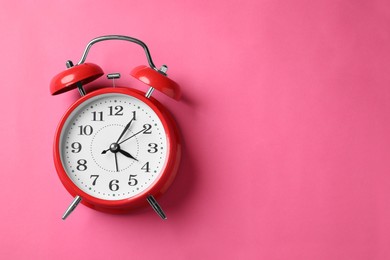 Photo of Red alarm clock on pink background, top view. Space for text