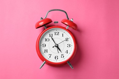 Photo of Red alarm clock on pink background, top view