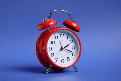 Photo of One red alarm clock on blue background