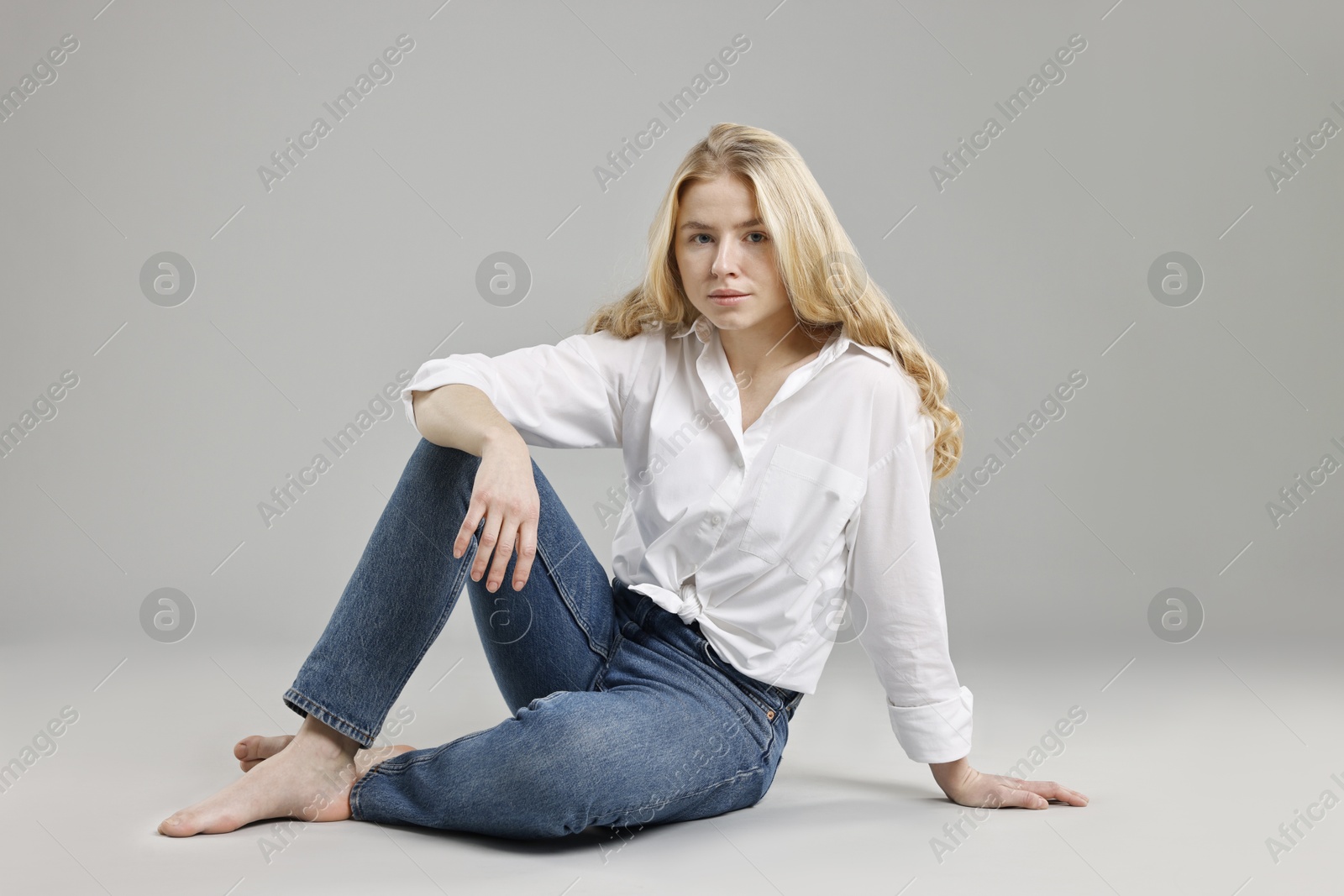 Photo of Beautiful young woman in stylish jeans on grey background