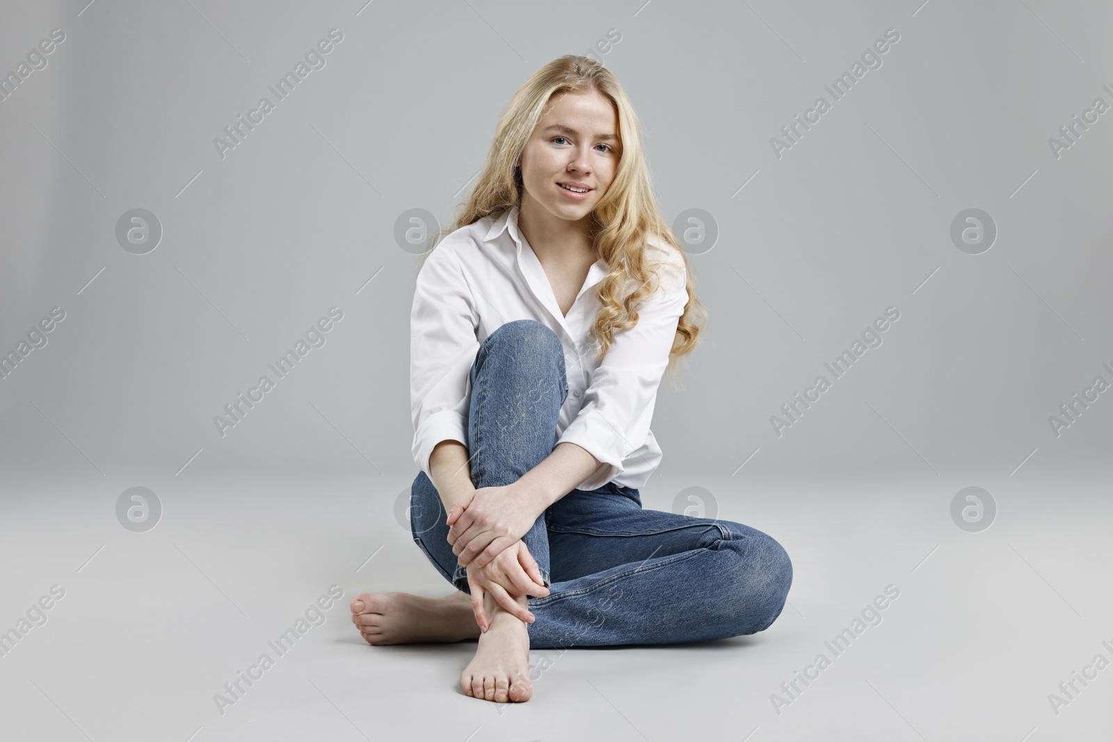 Photo of Smiling woman in stylish jeans on grey background