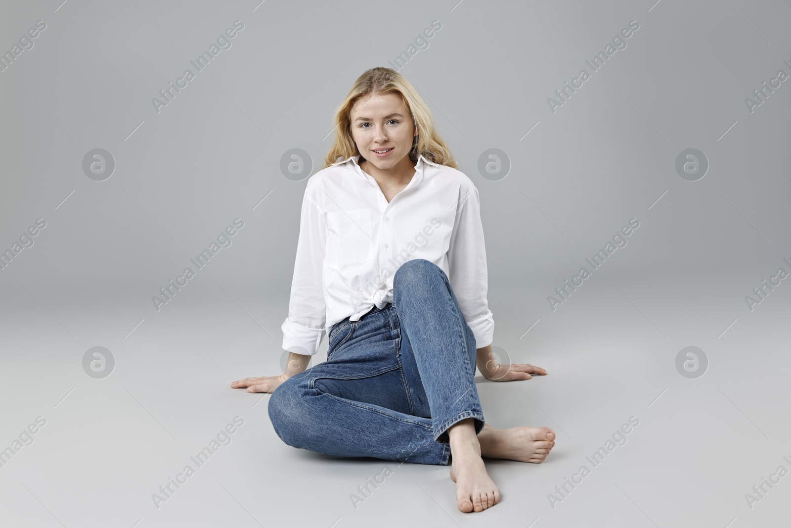 Photo of Smiling woman in stylish jeans on grey background