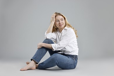 Photo of Smiling woman in stylish jeans on grey background