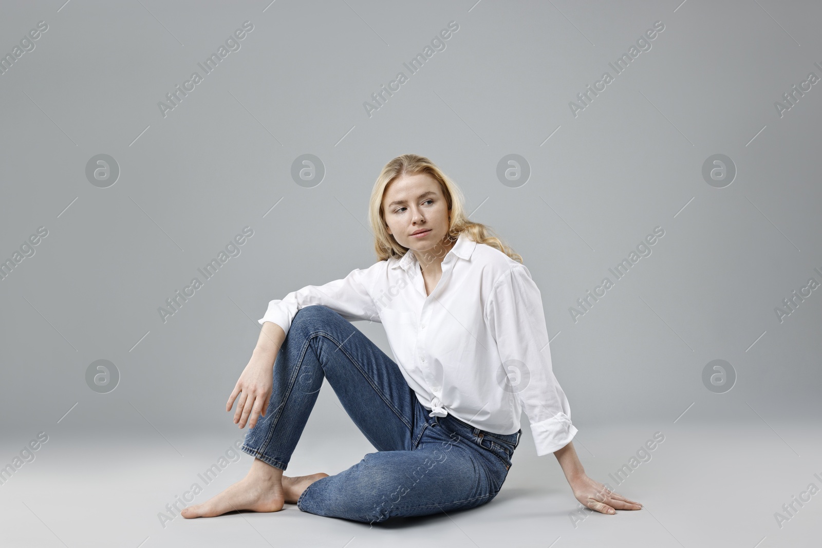 Photo of Beautiful young woman in stylish jeans on grey background