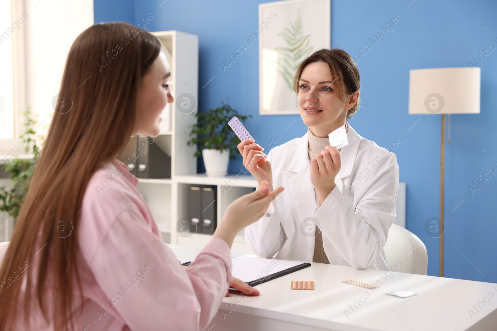 Photo of Gynecologist showing different contraceptive products to woman in clinic