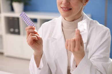 Photo of Gynecologist showing different contraceptive products in clinic, closeup